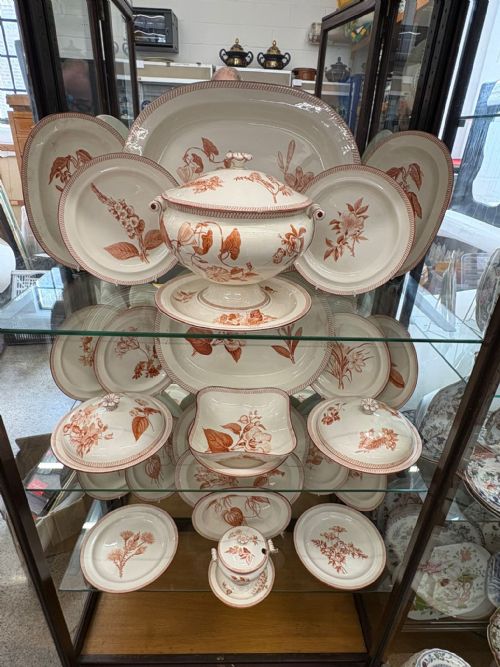 fig 1. A Victorian Wedgwood creamware dinner service decorated with terracotta transfer-printed botanical motifs, including plates, platters, covered dishes, and a pedestal tureen.
