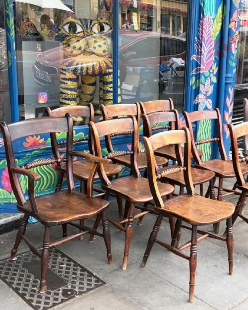 A set of ten early Victorian wooden dining chairs with turned legs, curved top rails, and solid timber seats, featuring two armchairs and eight side chairs. View II