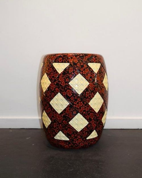 A barrel-shaped Victorian ceramic garden seat by Minton featuring cream lattice-patterned diamond panels against a dark background decorated with red floral blossom motifs. View II