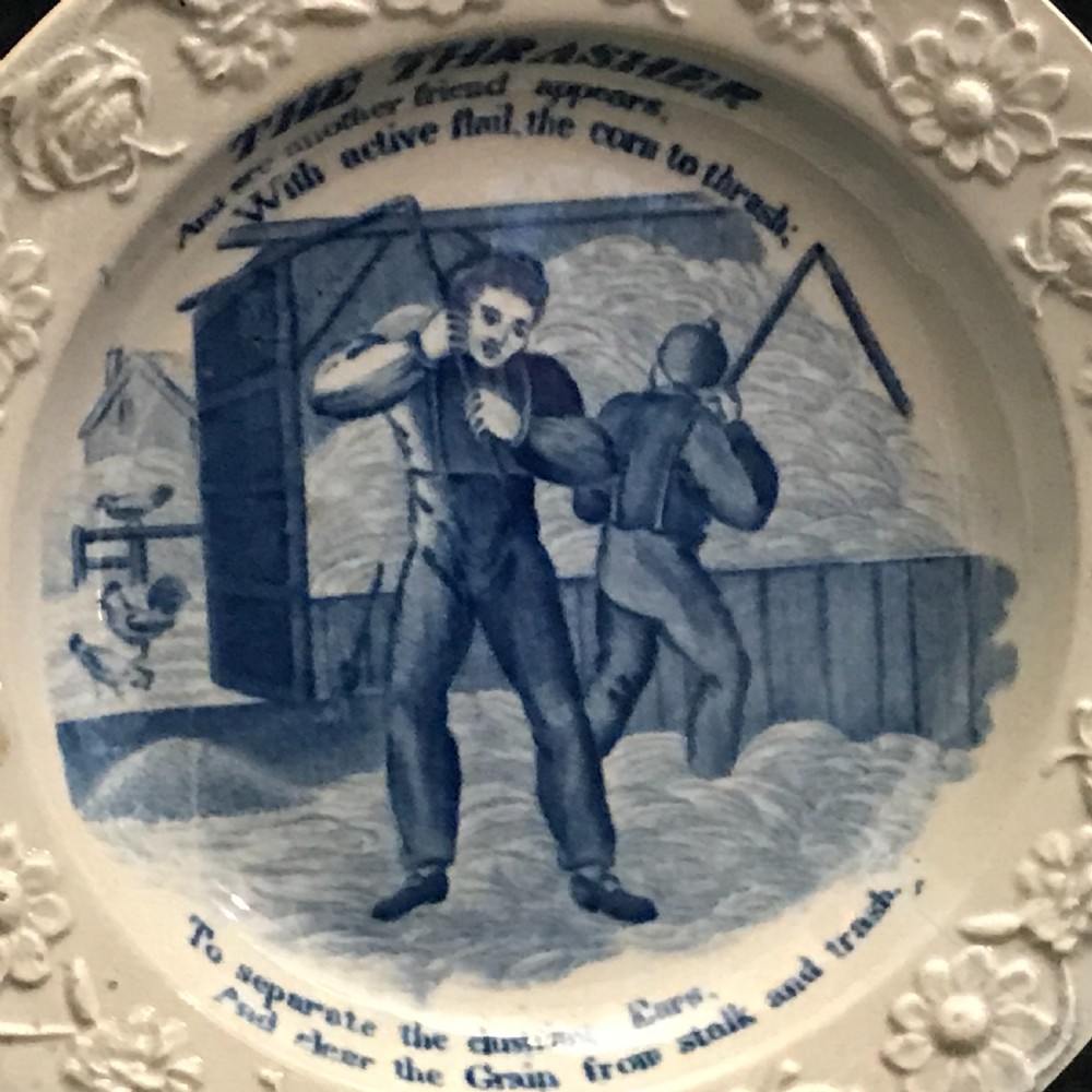 A set of four circular cream pearlware nursery plates featuring blue transfer-printed scenes of historical trades enclosed by moulded floral borders. View IV