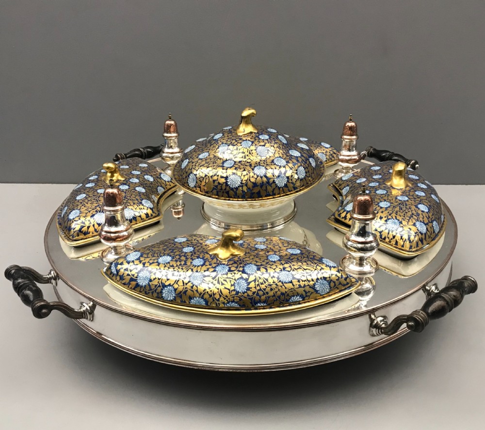 An early 19th-century Coalport porcelain supper set featuring cobalt blue and gold floral pattern covered dishes and condiment shakers set on a revolving silver-plated tray with dark wood handles.
