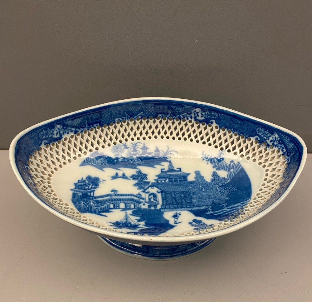 An eighteenth-century oval blue and white pearlware comport featuring reticulated pierced lattice work around the bowl and pedestal base, decorated with chinoiserie transfer patterns. View II