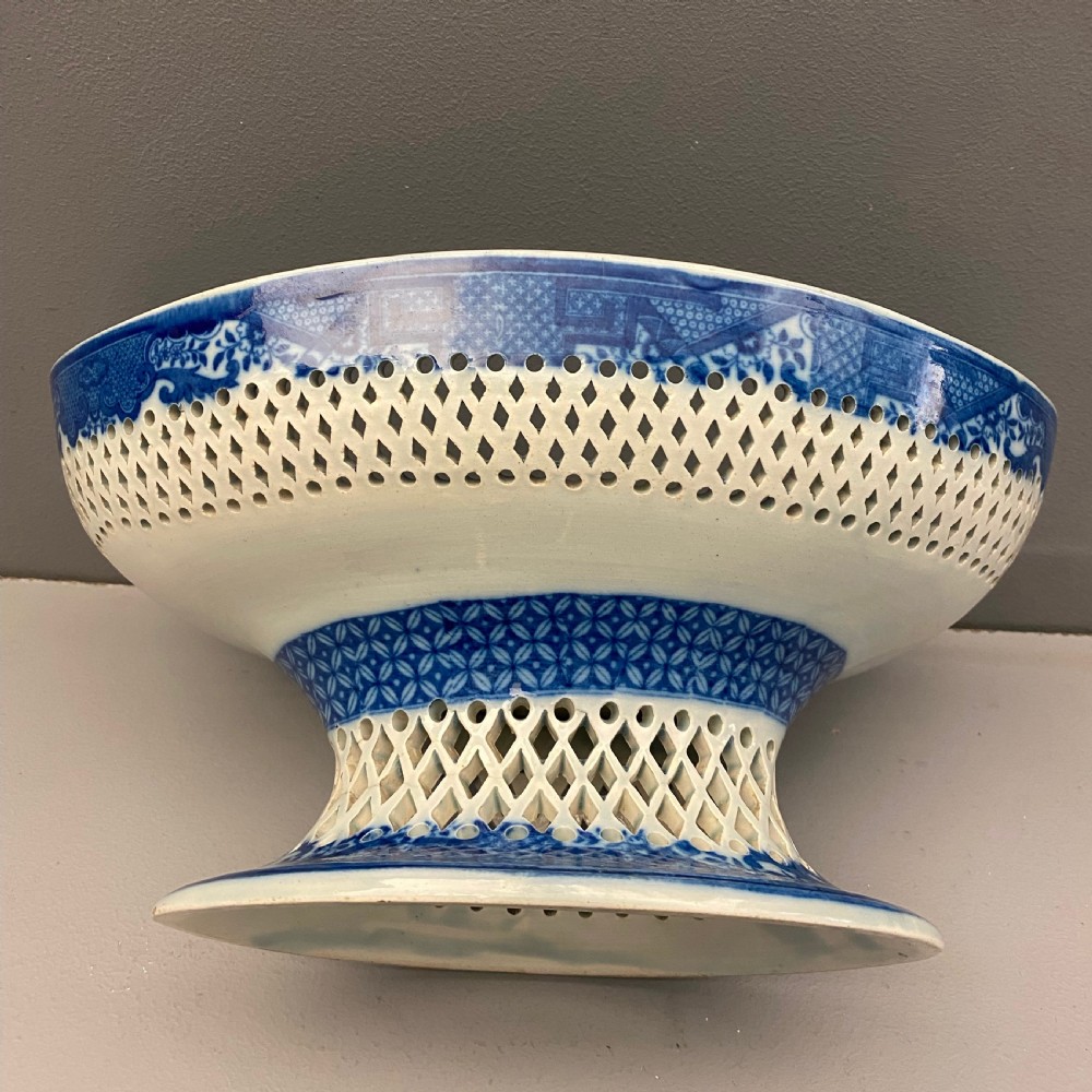An eighteenth-century oval blue and white pearlware comport featuring reticulated pierced lattice work around the bowl and pedestal base, decorated with chinoiserie transfer patterns. View III