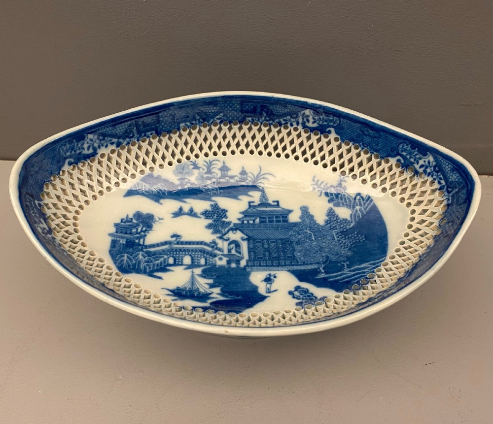 An eighteenth-century oval blue and white pearlware comport featuring reticulated pierced lattice work around the bowl and pedestal base, decorated with chinoiserie transfer patterns. View IV
