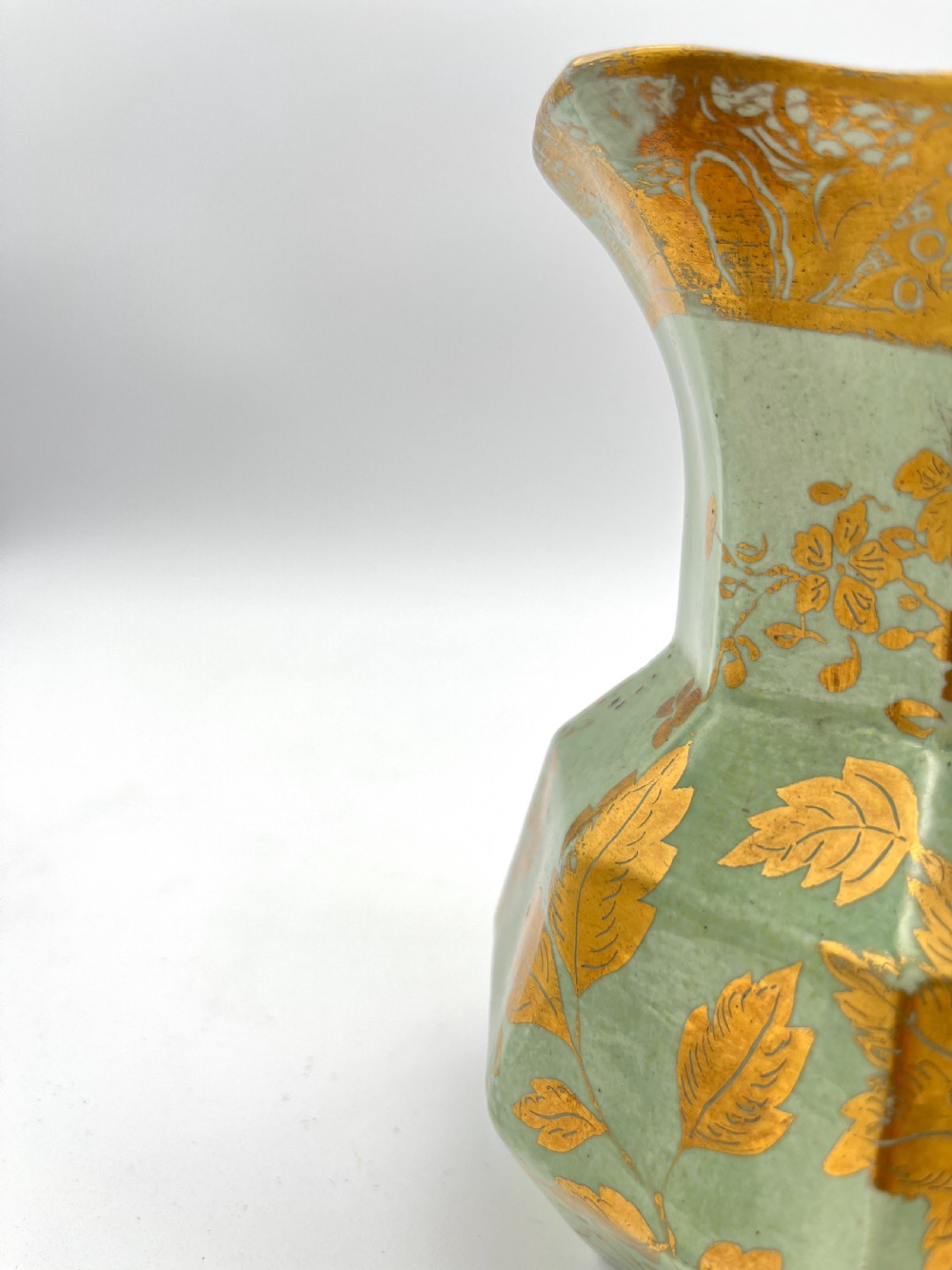 A set of three graduated octagonal sage green ironstone jugs decorated with gilded floral motifs and ornate moulded scroll handles. View IV