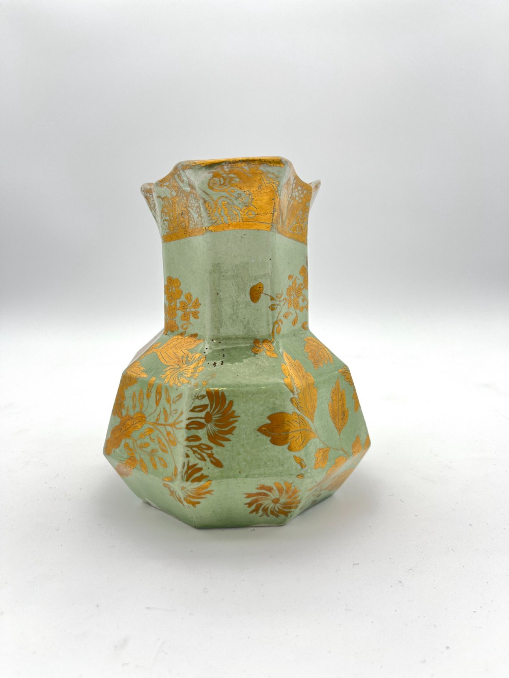 A set of three graduated octagonal sage green ironstone jugs decorated with gilded floral motifs and ornate moulded scroll handles. View V