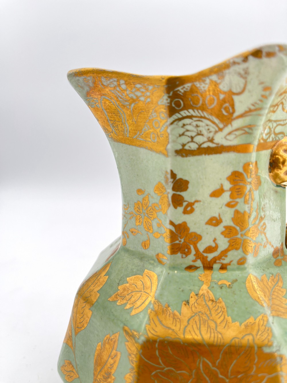 A set of three graduated octagonal sage green ironstone jugs decorated with gilded floral motifs and ornate moulded scroll handles. View VII