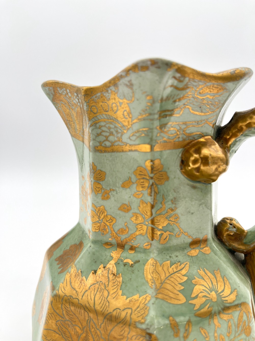 A set of three graduated octagonal sage green ironstone jugs decorated with gilded floral motifs and ornate moulded scroll handles. View VIII