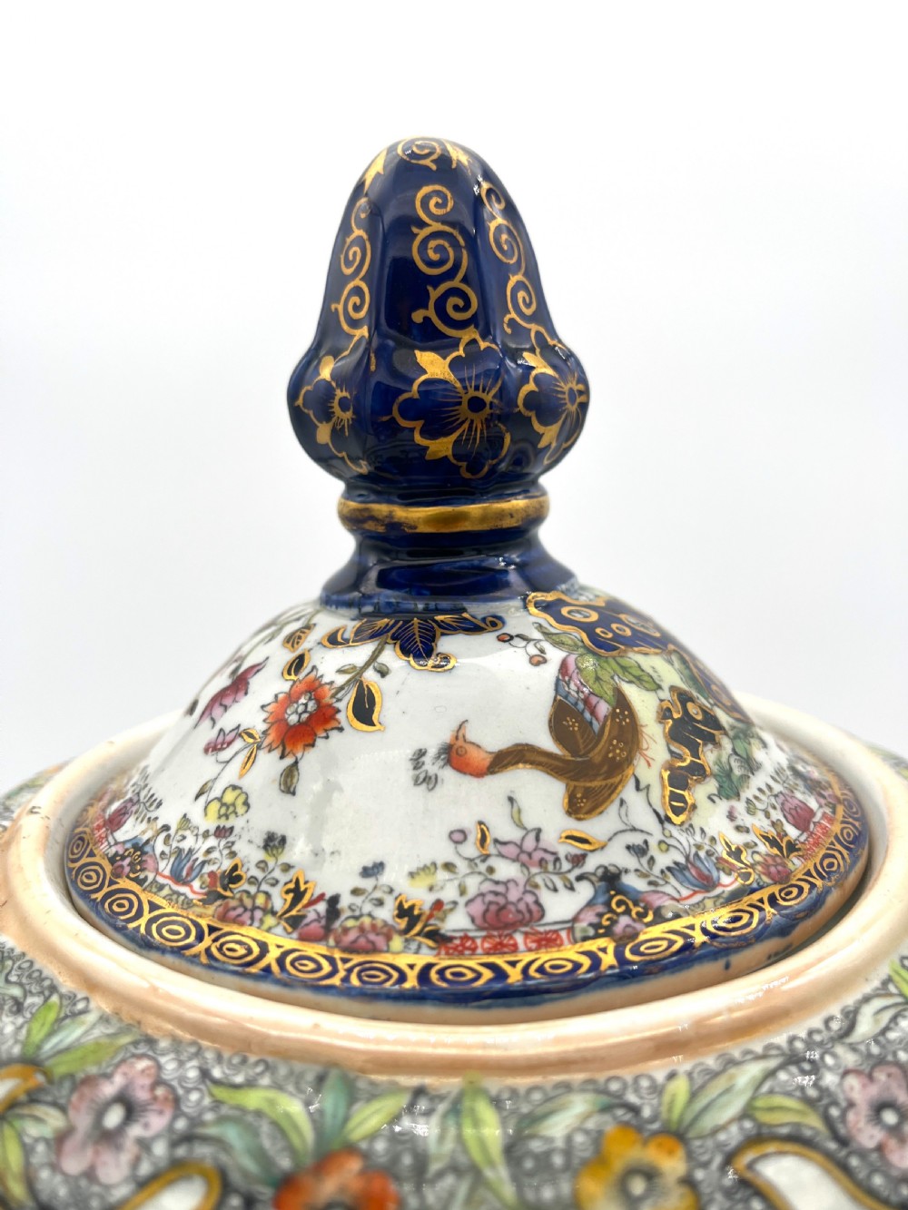 A pair of white and cobalt blue ceramic ironstone essence jars adorned with floral motifs, scroll handles, and fitted lids. View V