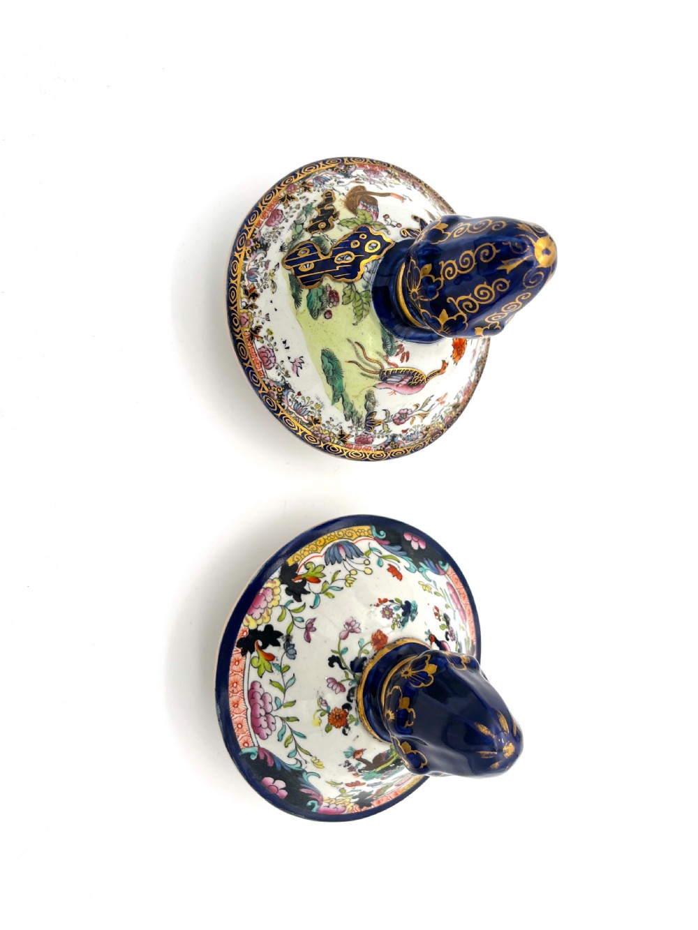 A pair of white and cobalt blue ceramic ironstone essence jars adorned with floral motifs, scroll handles, and fitted lids. View VII