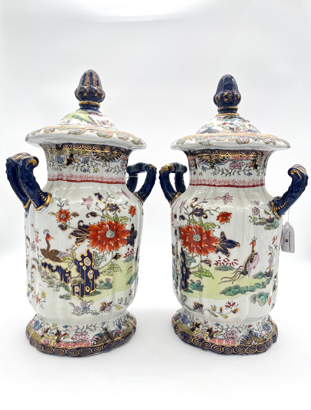 A pair of white and cobalt blue ceramic ironstone essence jars adorned with floral motifs, scroll handles, and fitted lids. View IX