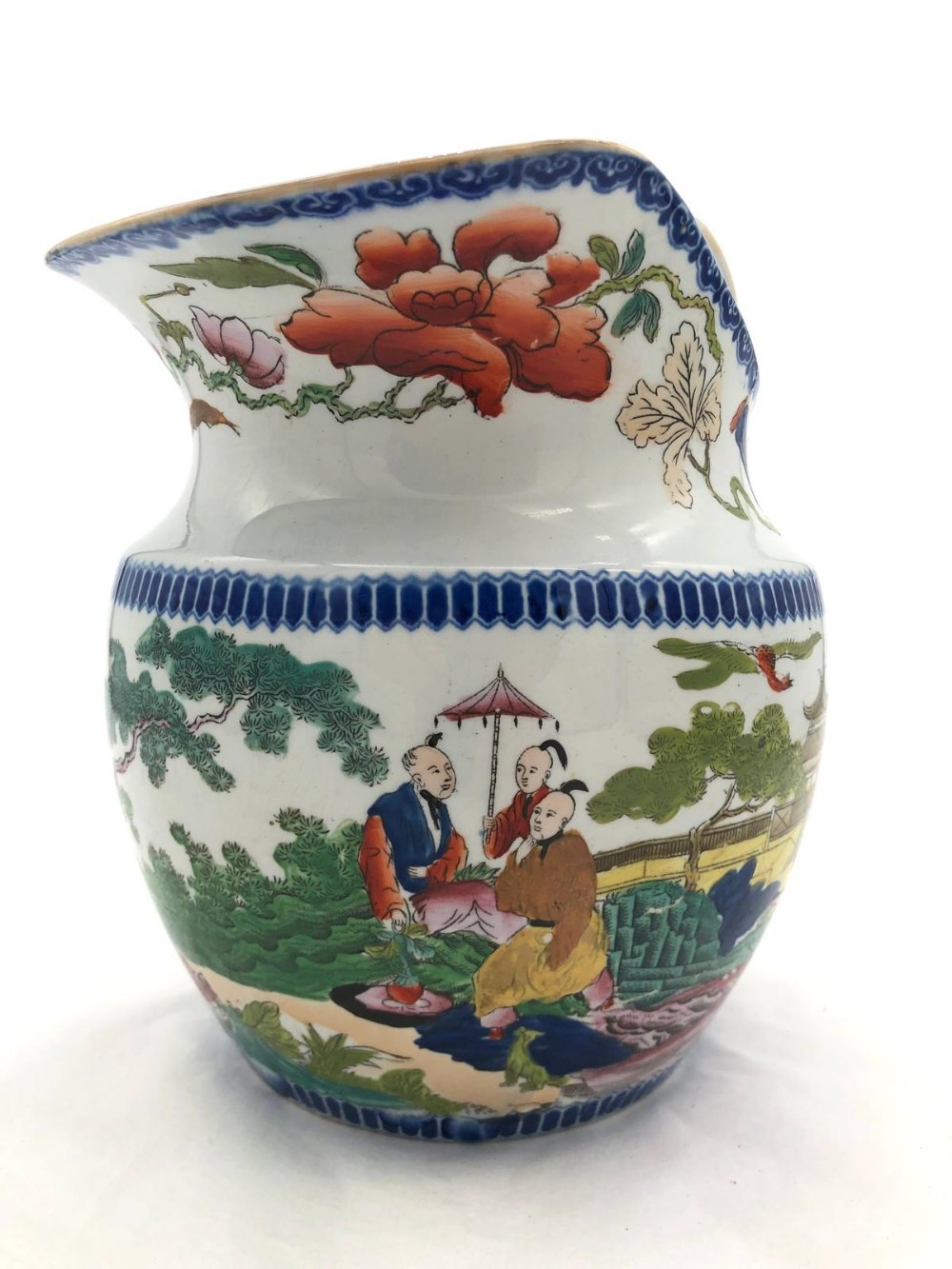 An antique Masons ironstone ceramic washbasin jug decorated with hand-painted Chinoiserie figures, trees, flowers, and a blue diaper pattern rim.