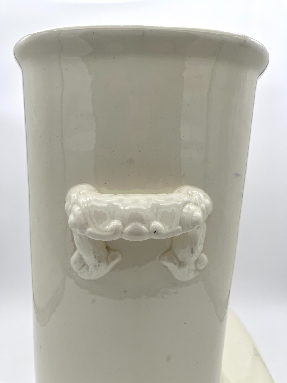 A cream-coloured glazed earthenware knee bath vessel with side handles and a stepped base profile. View IV