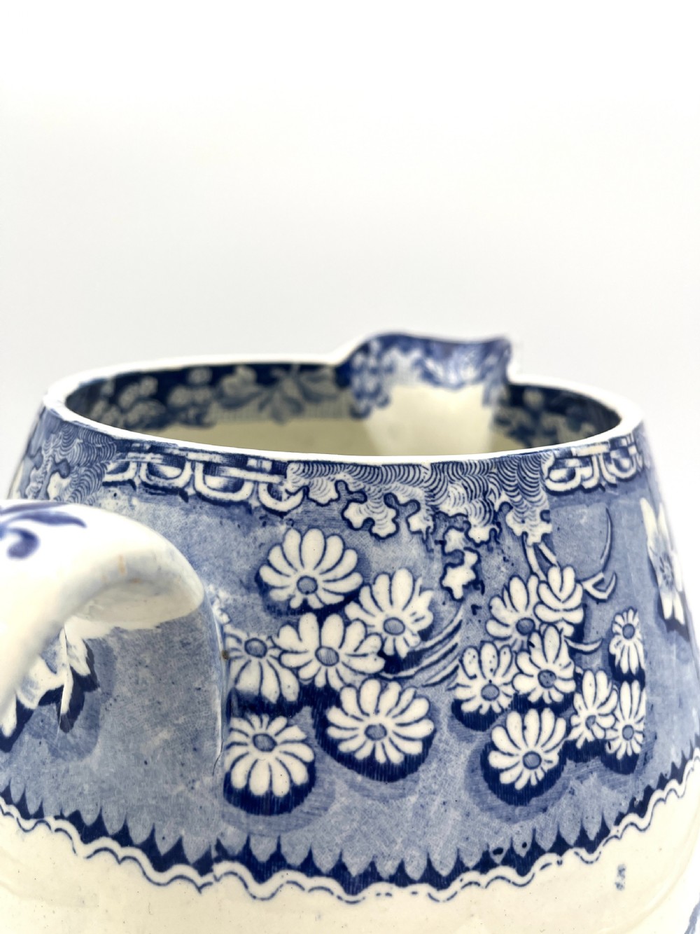 An antique blue and white earthenware footbath jug decorated with a floral upper band and a printed pastoral landscape scene. View VII