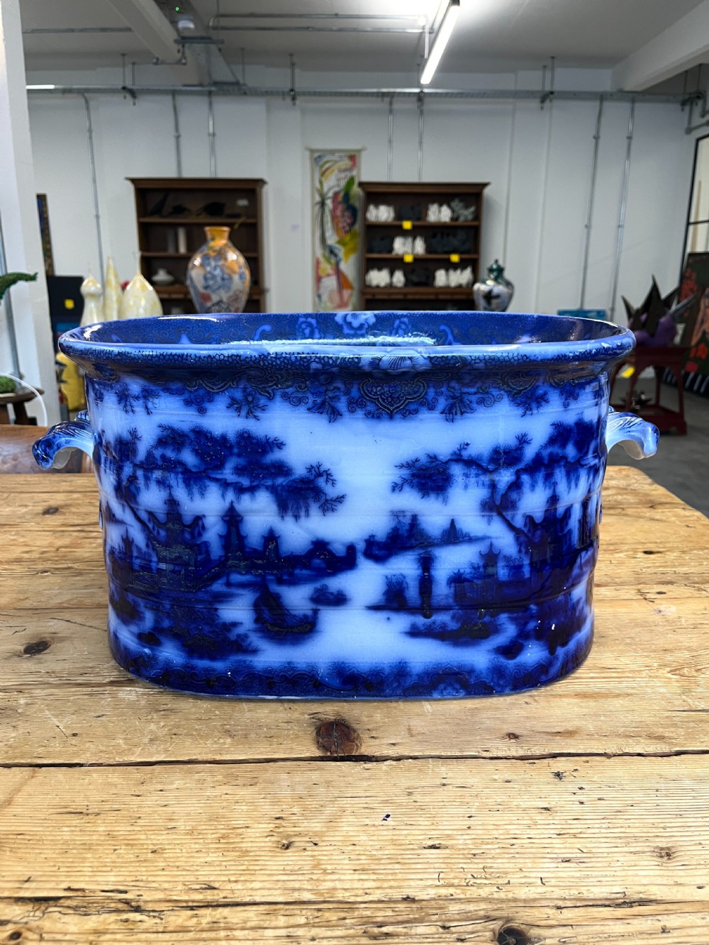 An oval flow blue ceramic foot bath featuring an oriental landscape transfer pattern with integrated side handles.
