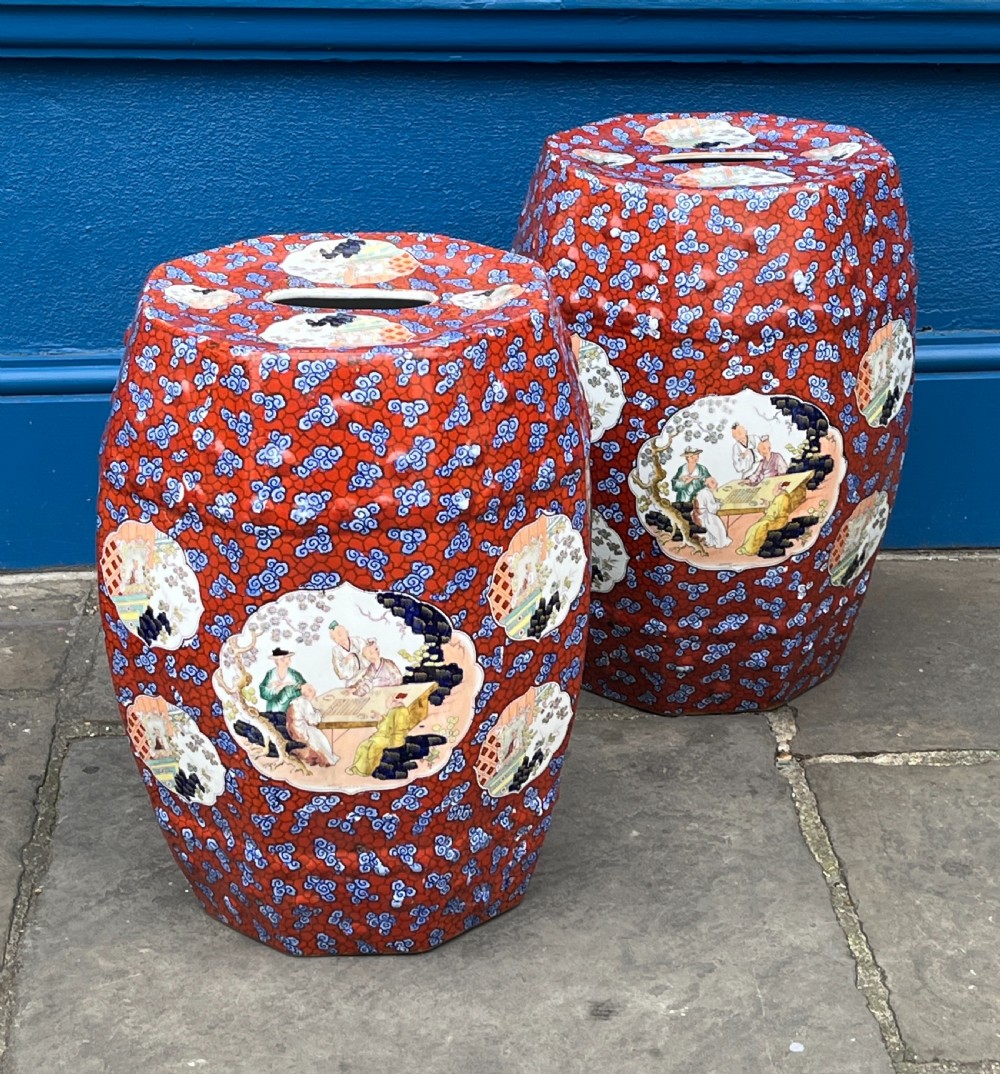 A pair of barrel-shaped clobbered ironstone garden seats decorated with red cloud patterns and reserve panels showing Chinese figures.