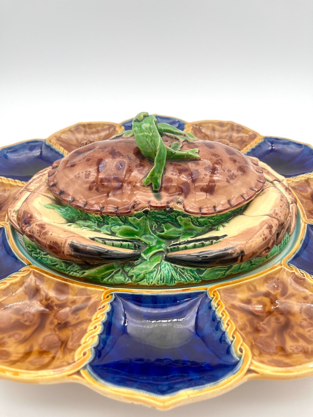 A Victorian Minton majolica ceramic tureen shaped as a crab with a green frog handle, resting on a blue and brown segmented platter. View II