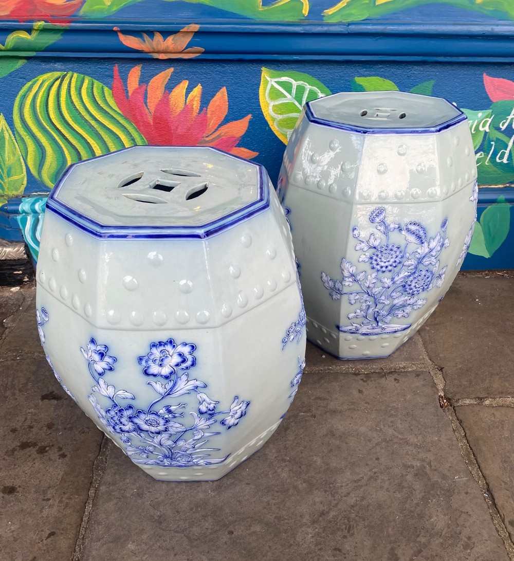 A pair of octagonal ceramic garden seats featuring a pale celadon glaze decorated with cobalt flow blue floral motifs and raised studs.