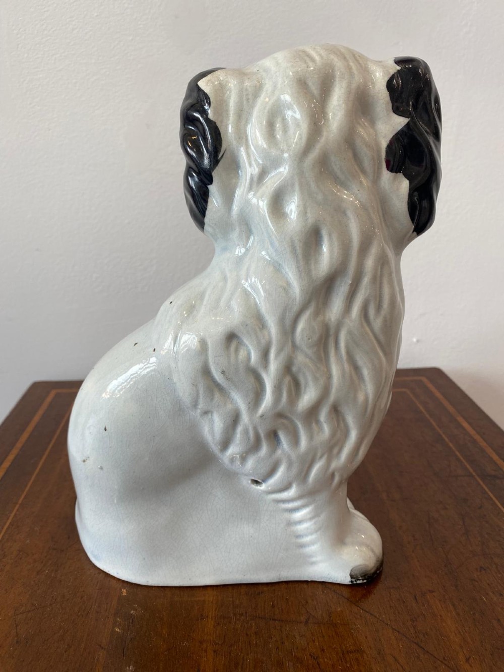A matching pair of Victorian white earthenware Staffordshire spaniel figurines painted with black coat markings and holding baskets of flowers in their mouths. View VII