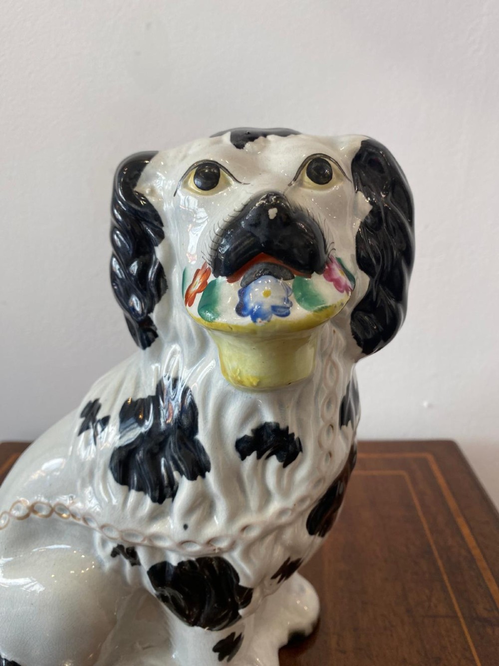 A matching pair of Victorian white earthenware Staffordshire spaniel figurines painted with black coat markings and holding baskets of flowers in their mouths. View XI