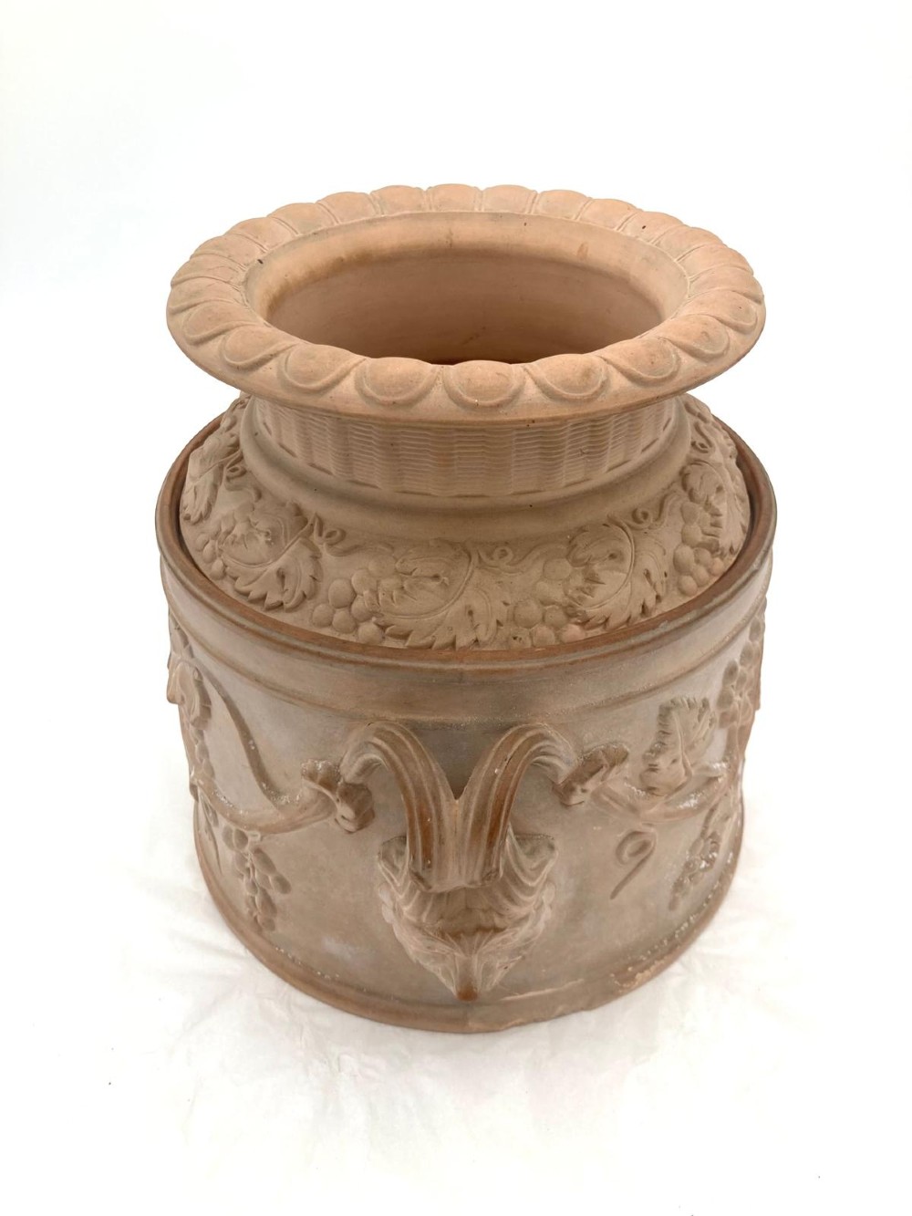 An unglazed terracotta wine cooler featuring twin scroll handles, a basketweave collar, and relief-moulded grape and vine leaf motifs. View II