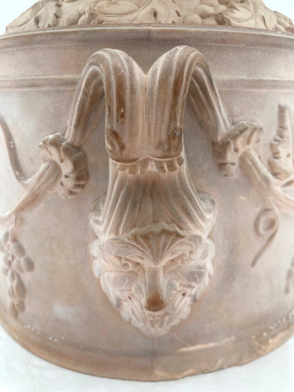 An unglazed terracotta wine cooler featuring twin scroll handles, a basketweave collar, and relief-moulded grape and vine leaf motifs. View IV