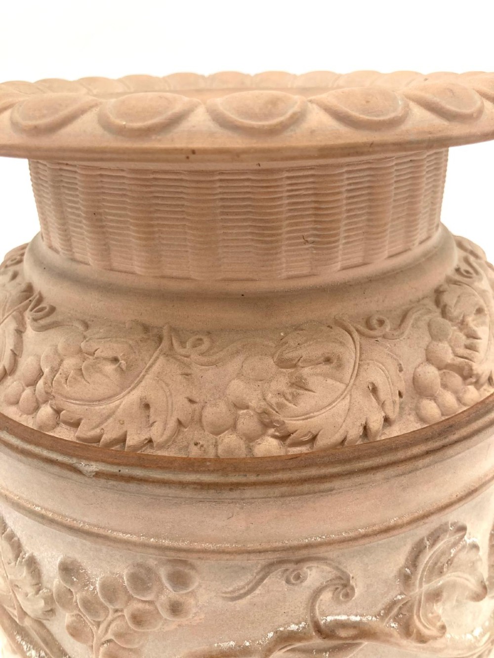 An unglazed terracotta wine cooler featuring twin scroll handles, a basketweave collar, and relief-moulded grape and vine leaf motifs. View VI
