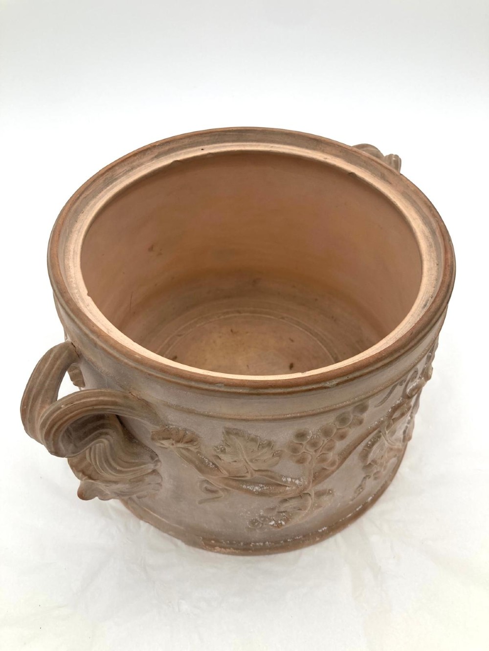 An unglazed terracotta wine cooler featuring twin scroll handles, a basketweave collar, and relief-moulded grape and vine leaf motifs. View VII