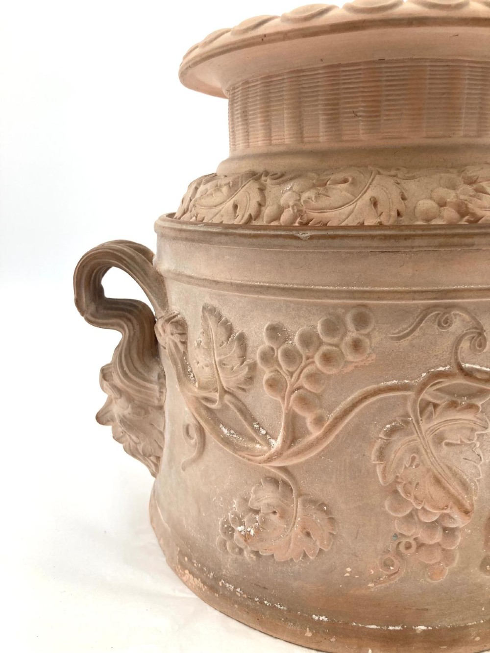 An unglazed terracotta wine cooler featuring twin scroll handles, a basketweave collar, and relief-moulded grape and vine leaf motifs. View XI
