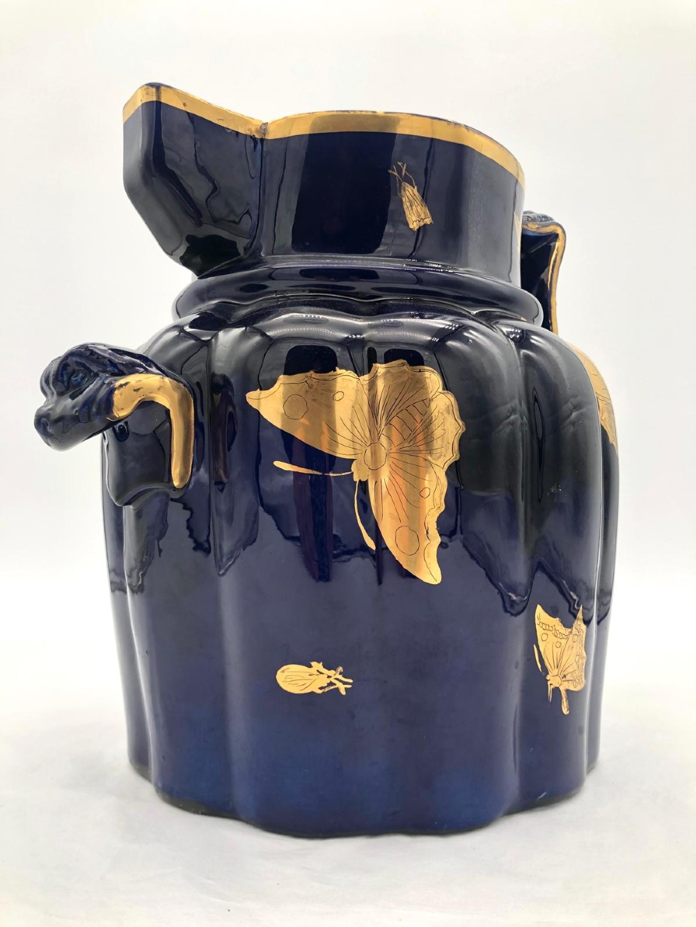 A deep cobalt blue porcelain jug decorated with gilded butterfly motifs and a wide spout, dating to circa 1820. View VIII