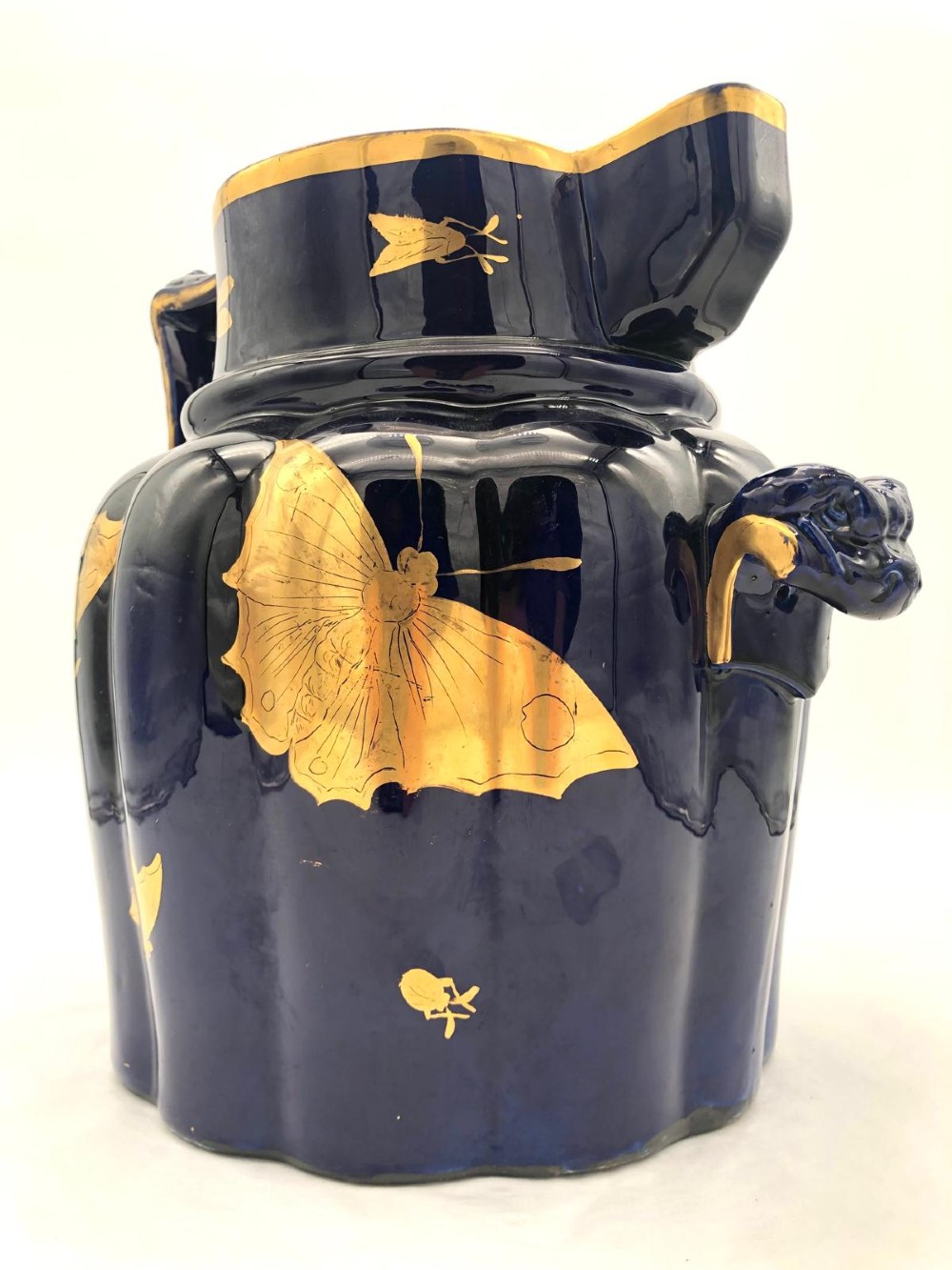 A deep cobalt blue porcelain jug decorated with gilded butterfly motifs and a wide spout, dating to circa 1820. View IX