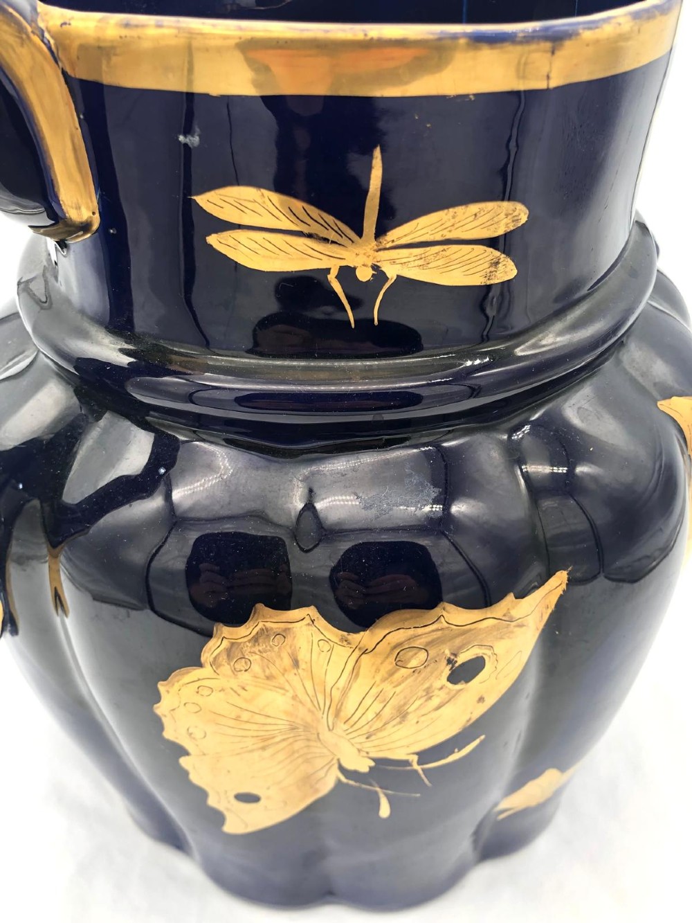 A deep cobalt blue porcelain jug decorated with gilded butterfly motifs and a wide spout, dating to circa 1820. View XI