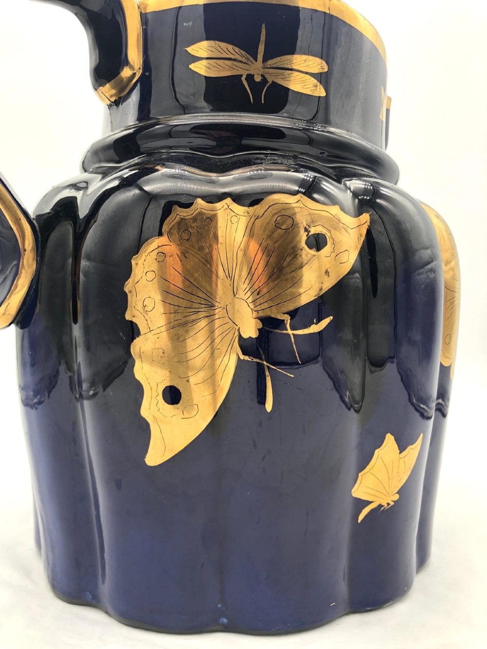 A deep cobalt blue porcelain jug decorated with gilded butterfly motifs and a wide spout, dating to circa 1820. View XII