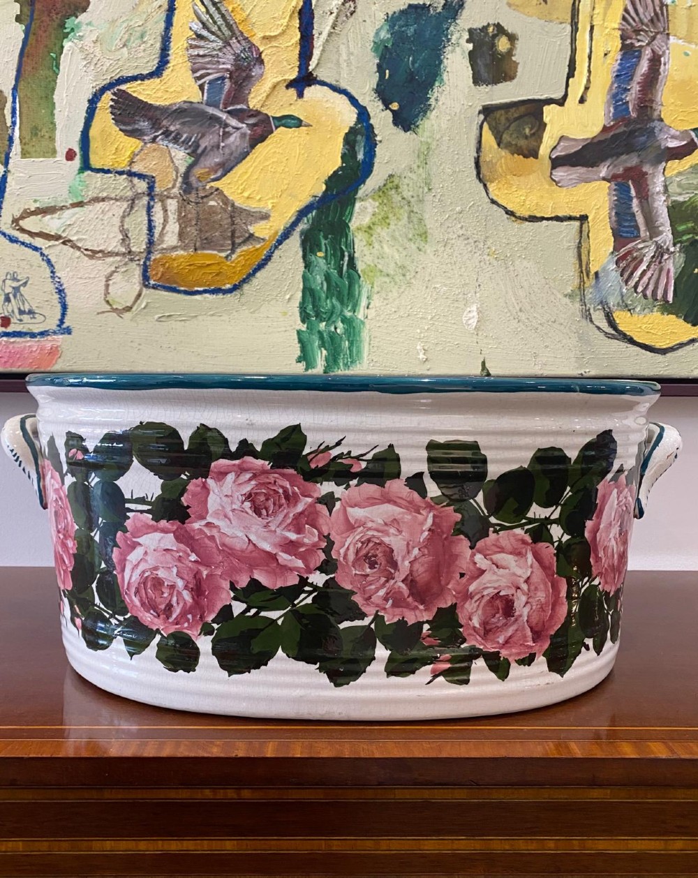 An oval white glazed ceramic footbath decorated with hand-painted pink cabbage roses, green foliage, a green painted rim, and twin side handles. View II