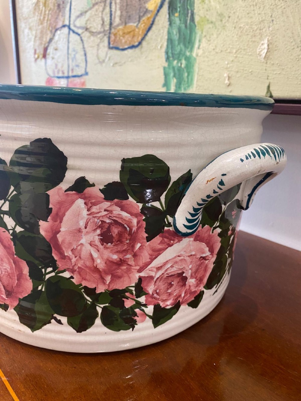 An oval white glazed ceramic footbath decorated with hand-painted pink cabbage roses, green foliage, a green painted rim, and twin side handles. View III