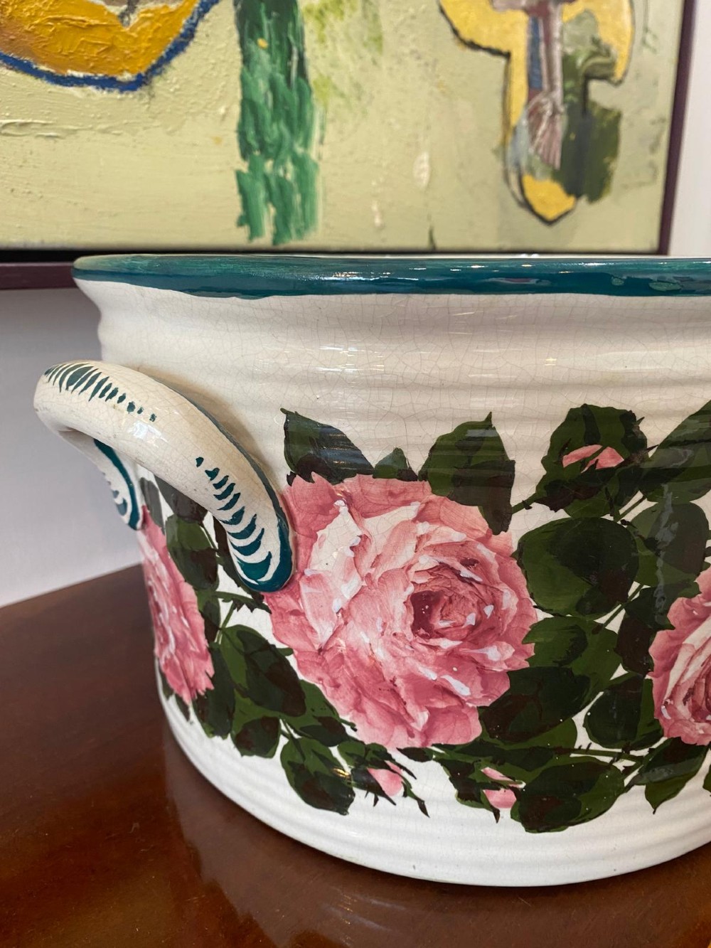 An oval white glazed ceramic footbath decorated with hand-painted pink cabbage roses, green foliage, a green painted rim, and twin side handles. View IV
