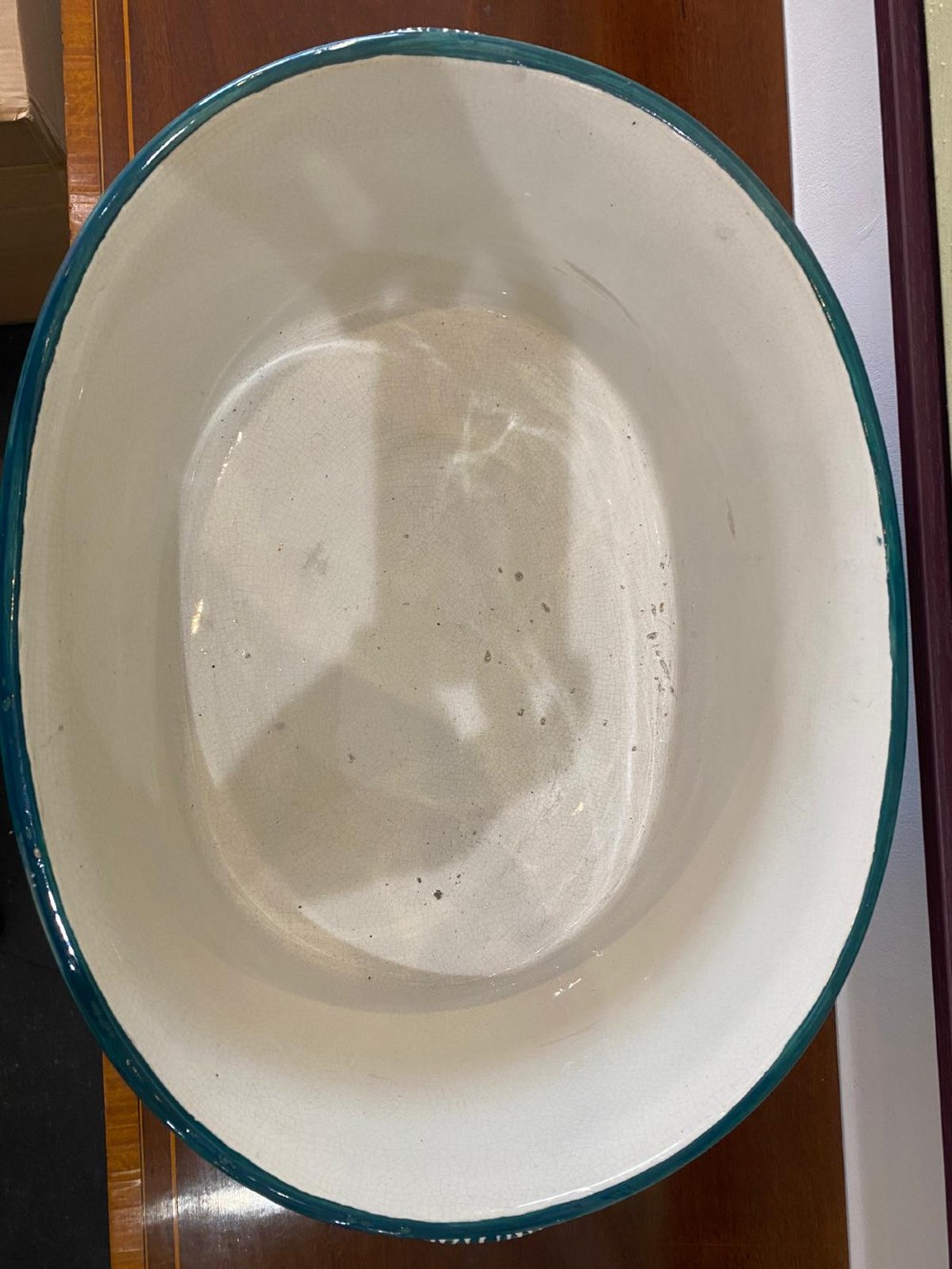 An oval white glazed ceramic footbath decorated with hand-painted pink cabbage roses, green foliage, a green painted rim, and twin side handles. View V