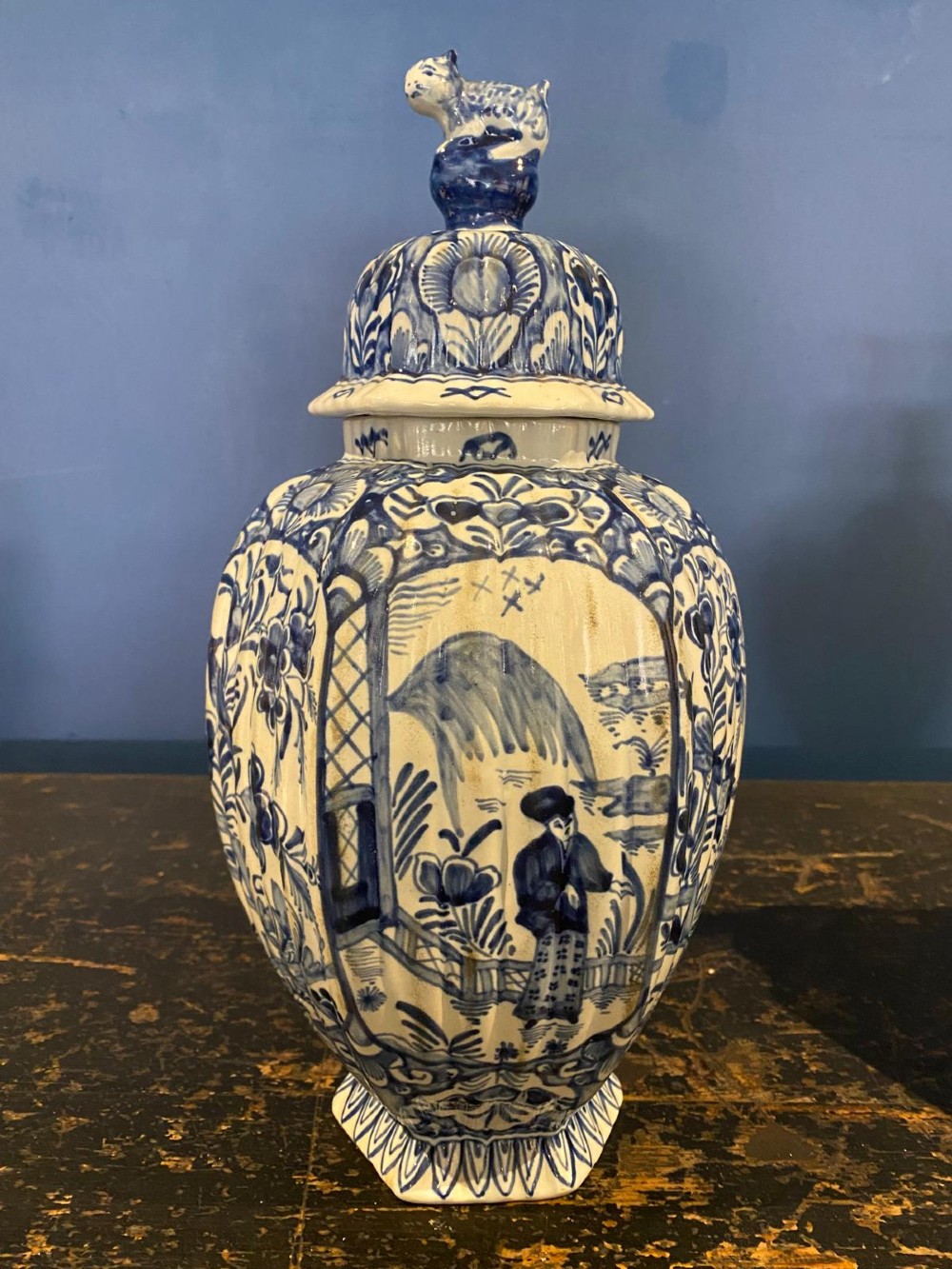 A pair of octagonal blue and white tin-glazed earthenware lidded vases decorated with hand-painted chinoiserie scenes and animal finials. View II