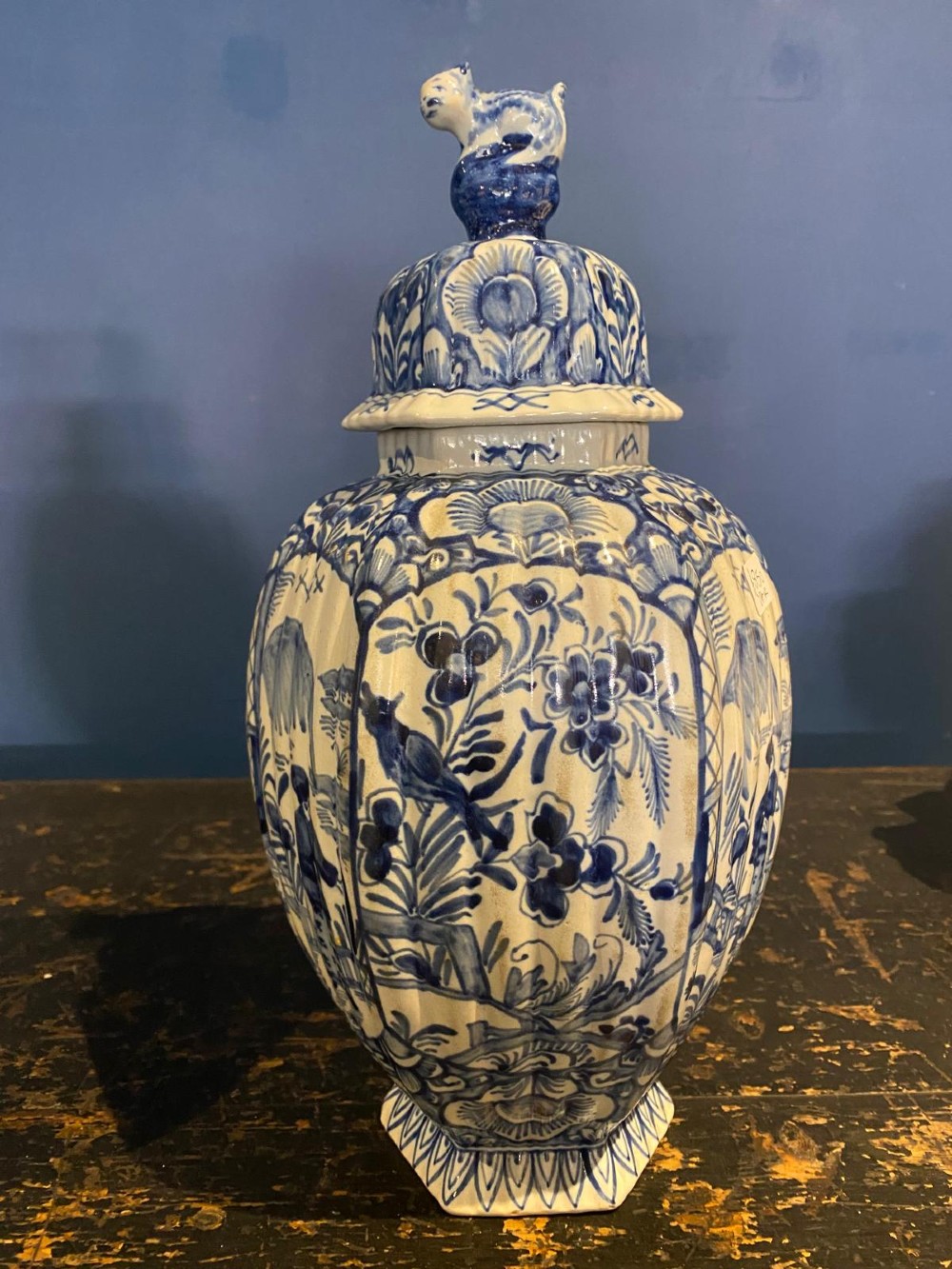 A pair of octagonal blue and white tin-glazed earthenware lidded vases decorated with hand-painted chinoiserie scenes and animal finials. View III