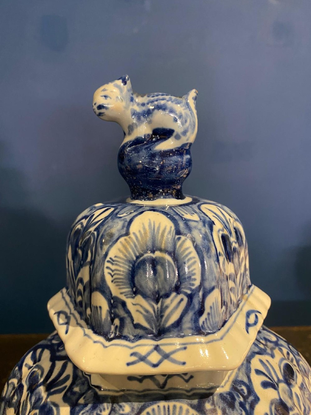 A pair of octagonal blue and white tin-glazed earthenware lidded vases decorated with hand-painted chinoiserie scenes and animal finials. View IX