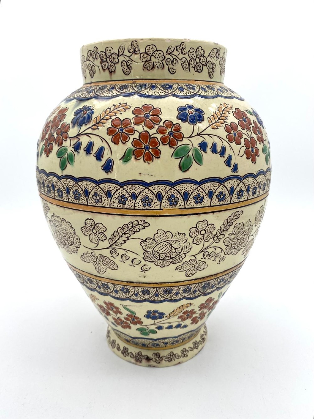 A late 19th-century bulbous Thoune earthenware vase decorated with hand-painted floral slipware motifs in terracotta, blue, and green over a cream background.