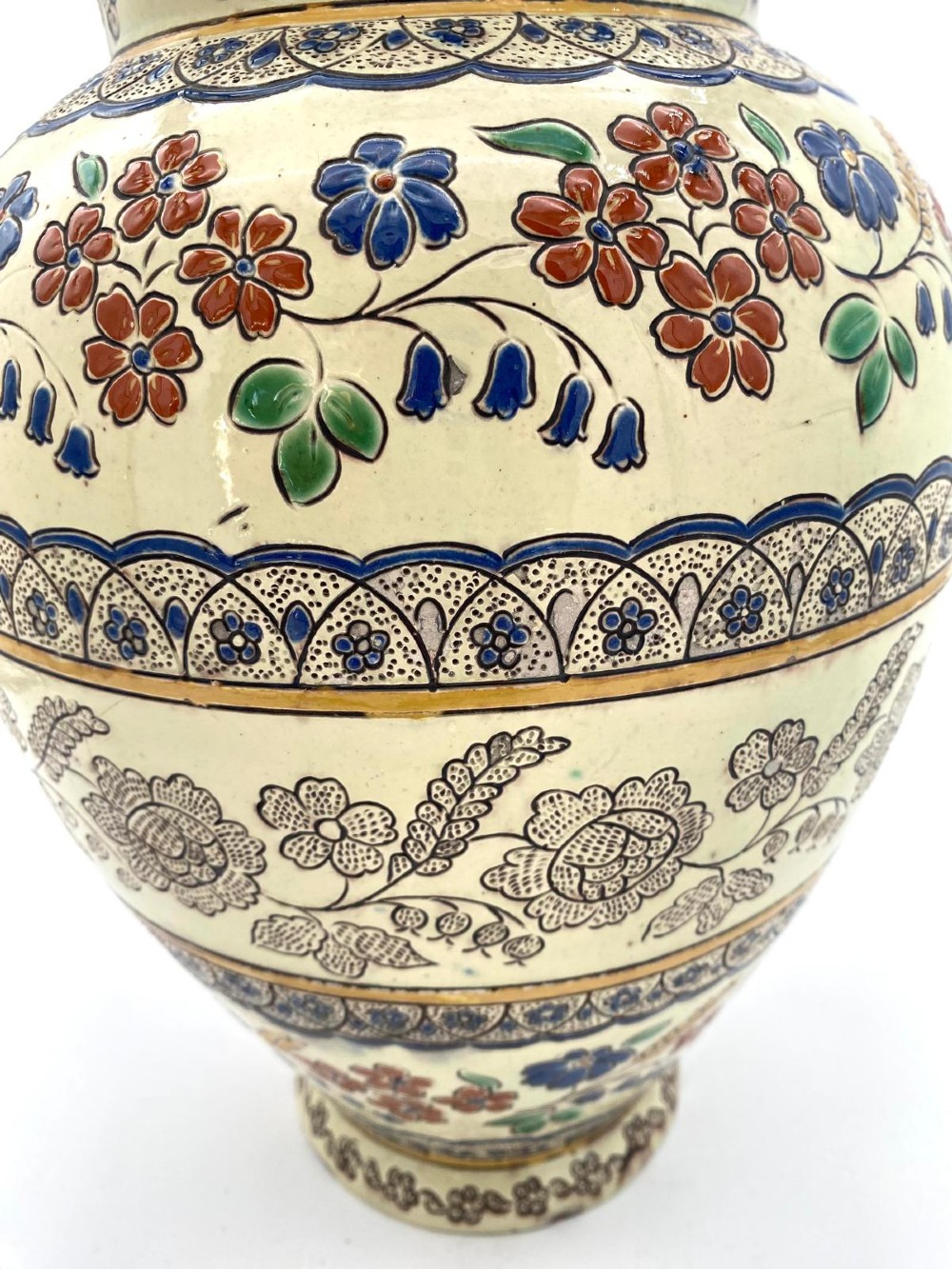 A late 19th-century bulbous Thoune earthenware vase decorated with hand-painted floral slipware motifs in terracotta, blue, and green over a cream background. View V