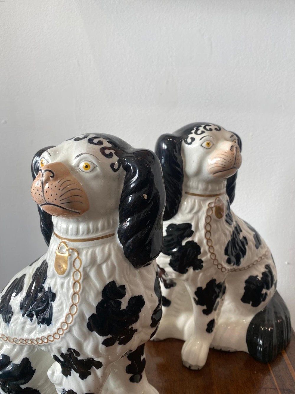 A pair of moulded white glazed ceramic Staffordshire spaniels decorated with hand-painted black patches, yellow eyes, and gilded chain collars. View II