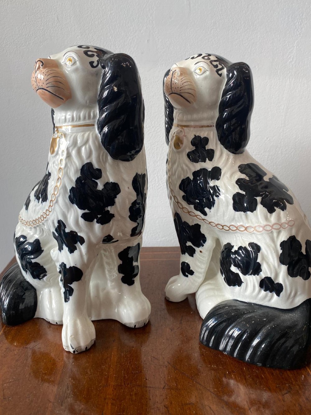 A pair of moulded white glazed ceramic Staffordshire spaniels decorated with hand-painted black patches, yellow eyes, and gilded chain collars. View IV