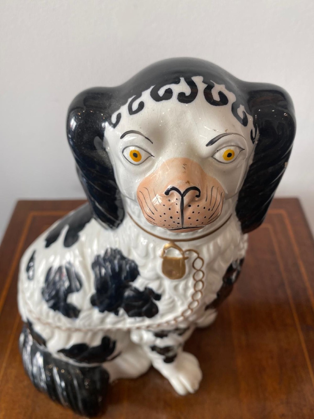 A pair of moulded white glazed ceramic Staffordshire spaniels decorated with hand-painted black patches, yellow eyes, and gilded chain collars. View V