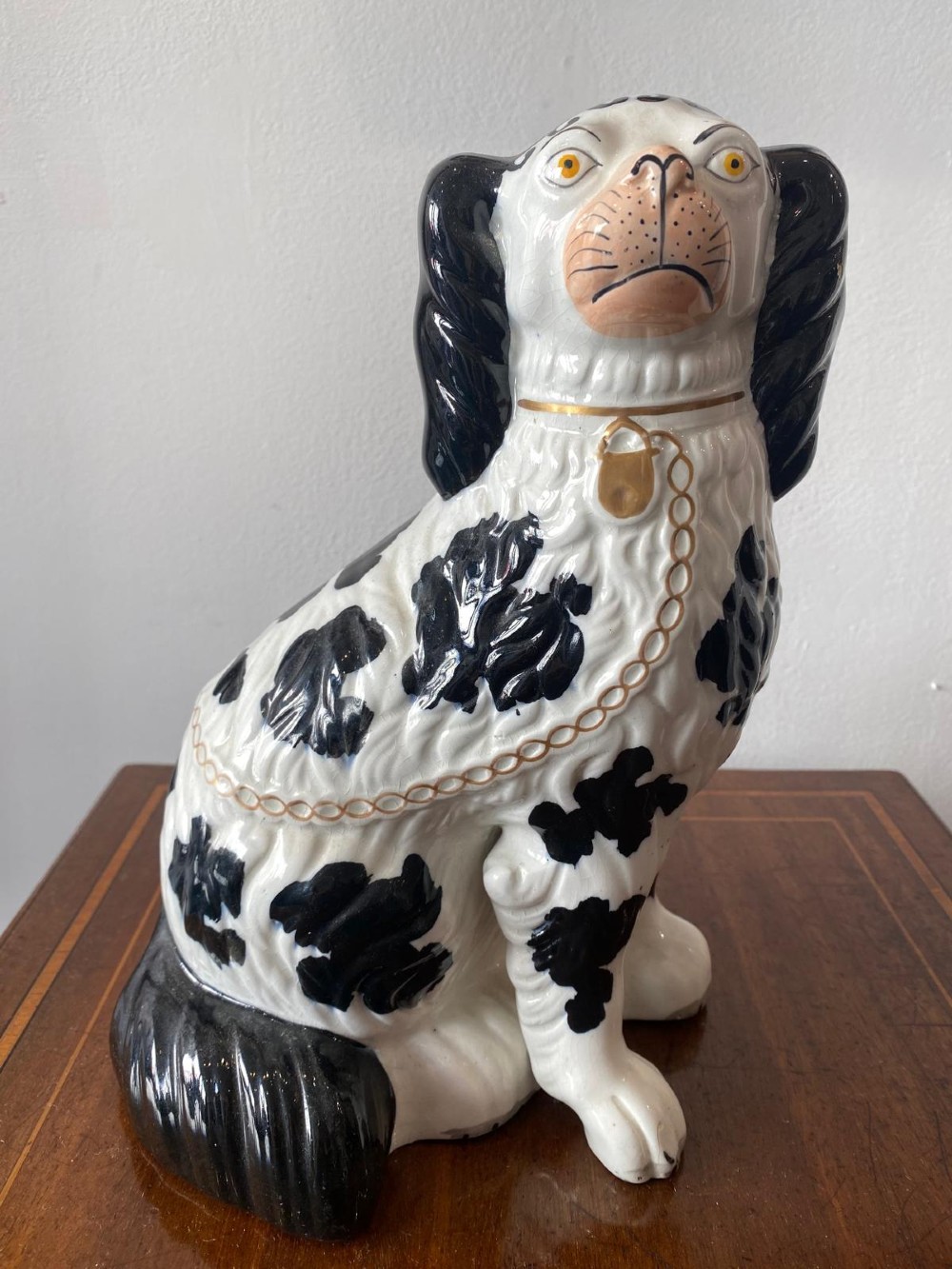 A pair of moulded white glazed ceramic Staffordshire spaniels decorated with hand-painted black patches, yellow eyes, and gilded chain collars. View VI