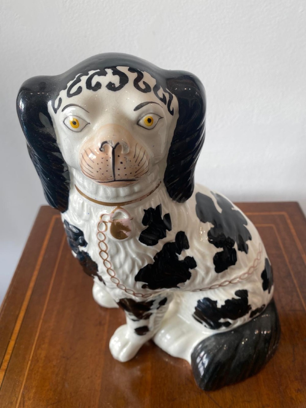 A pair of moulded white glazed ceramic Staffordshire spaniels decorated with hand-painted black patches, yellow eyes, and gilded chain collars. View X