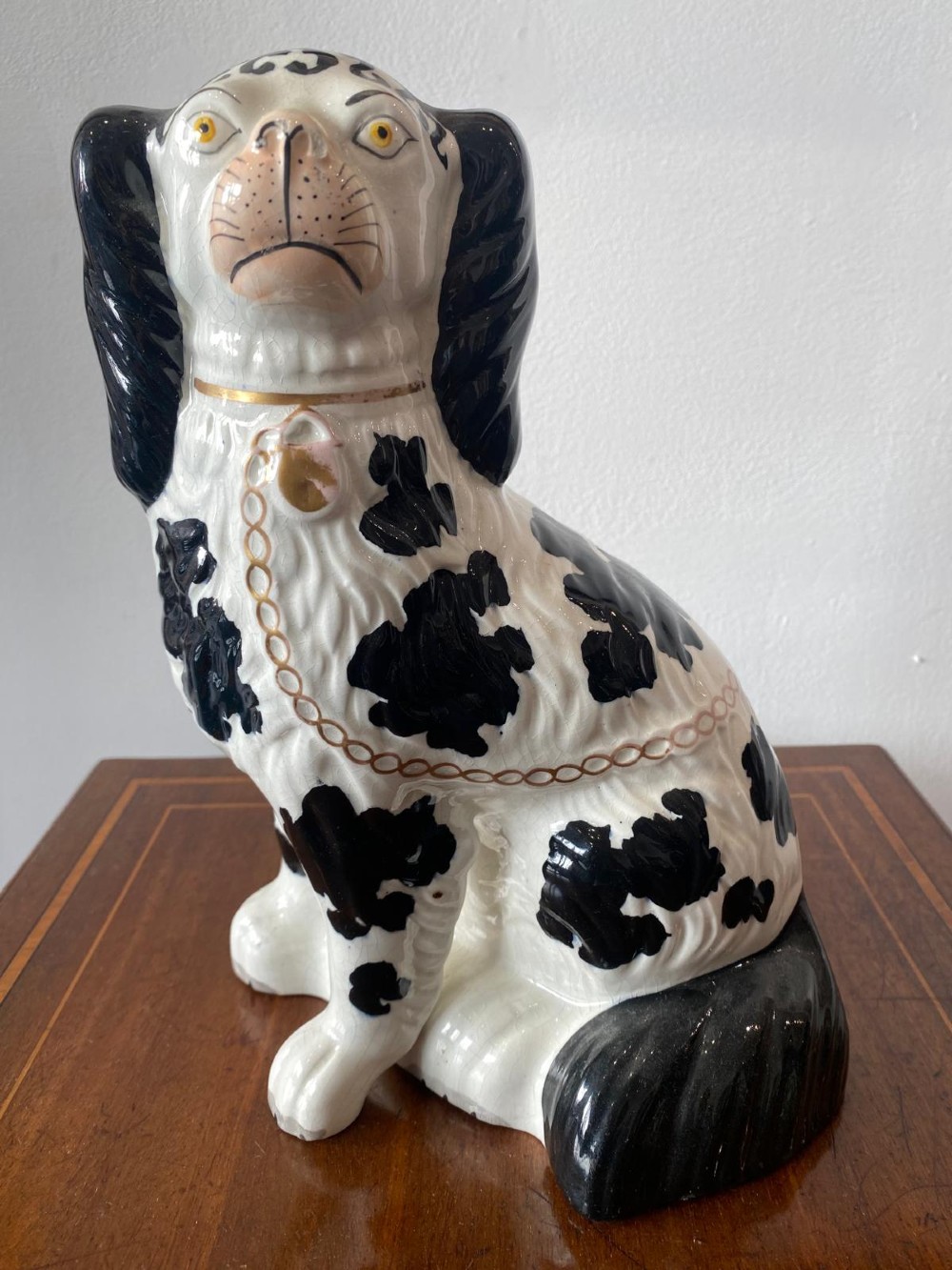 A pair of moulded white glazed ceramic Staffordshire spaniels decorated with hand-painted black patches, yellow eyes, and gilded chain collars. View XI