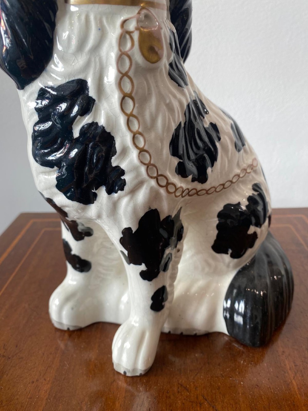 A pair of moulded white glazed ceramic Staffordshire spaniels decorated with hand-painted black patches, yellow eyes, and gilded chain collars. View XII