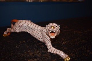 A hand-painted orange fishnet patterned porcelain jaguar sculpture in a prowling stance with gold paws and snout.